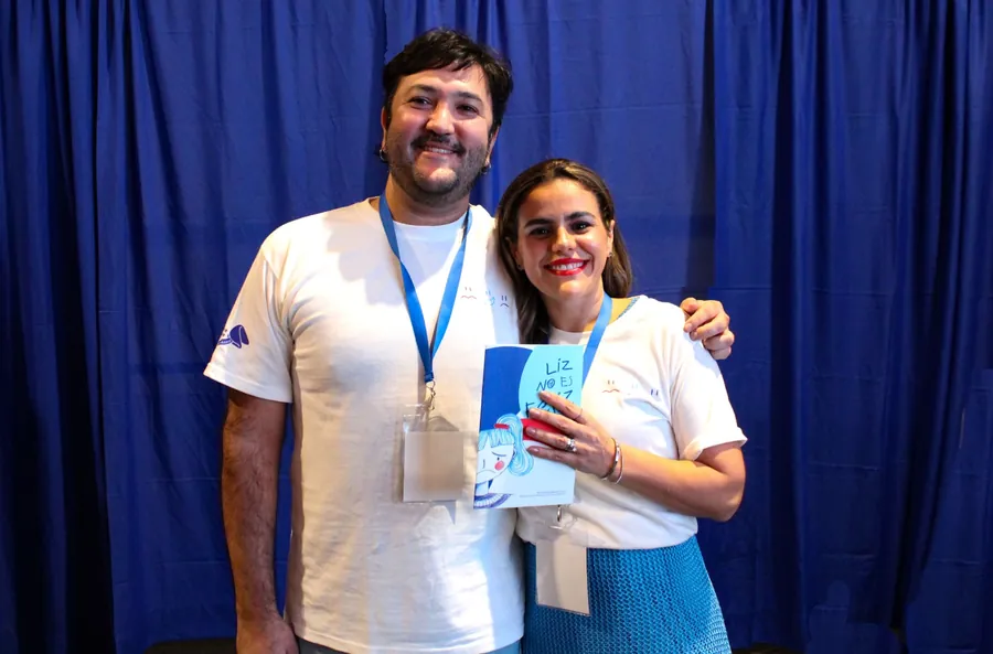 Dos integrantes del equipo de Fortune Cookie sonríen sosteniendo un ejemplar de Liz no es Feliz